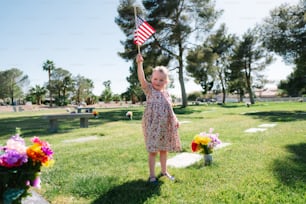 Ein kleines Mädchen mit einer amerikanischen Flagge auf einem Friedhof