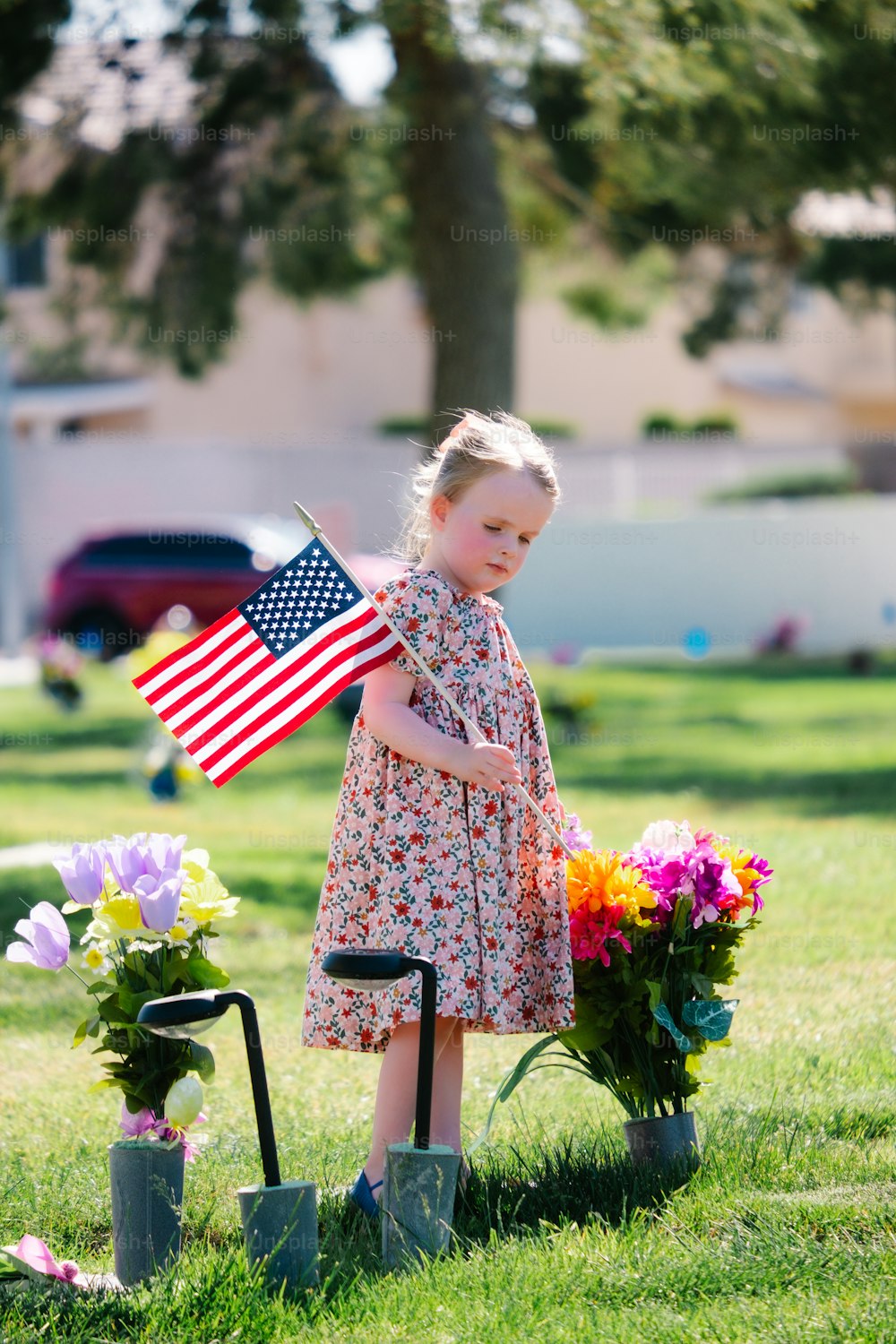 a little girl standing in the grass with a flag