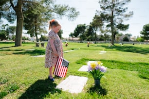 墓地でアメリカの国旗を持つ少女