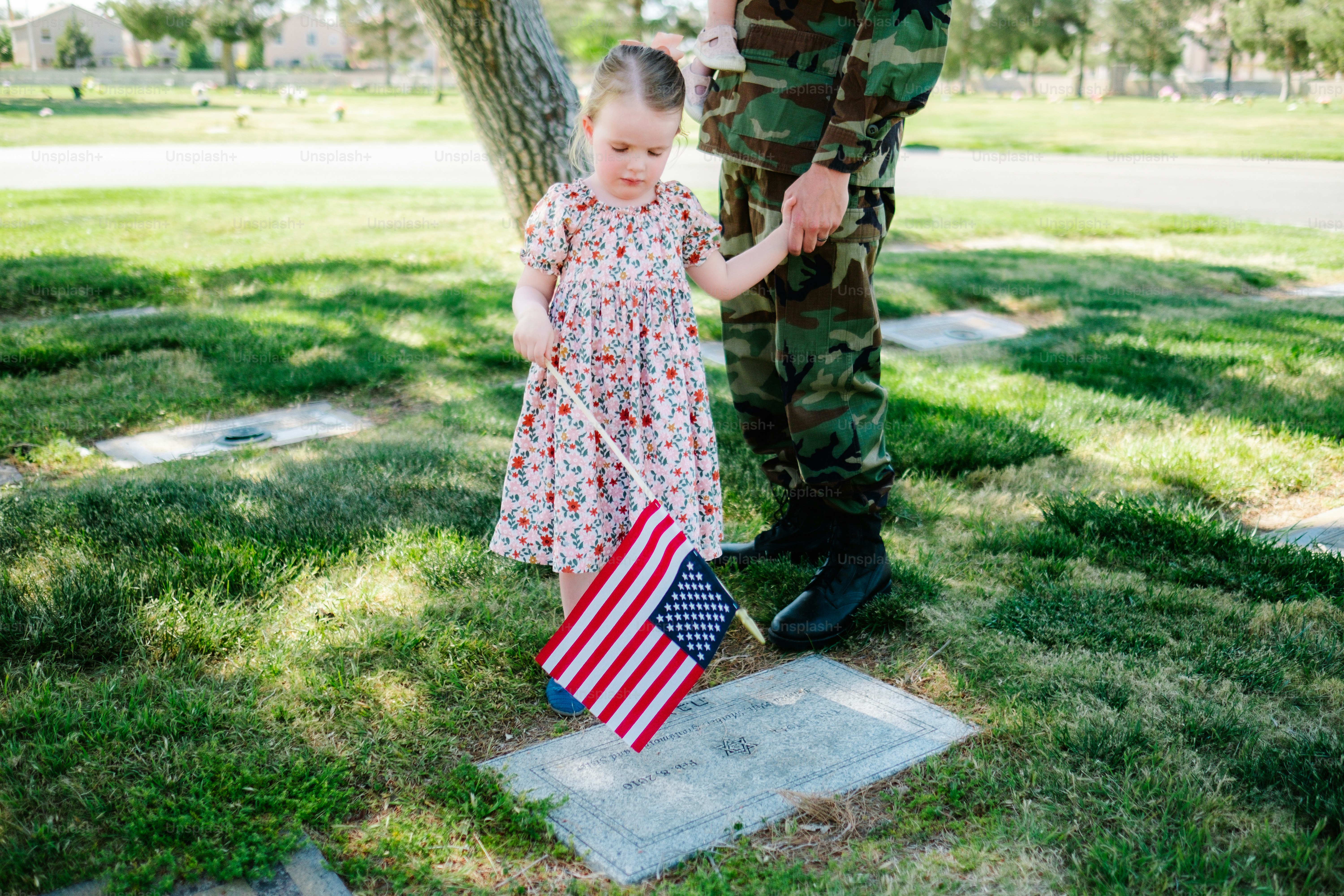 a little girl standing next to a soldier holding an american flag