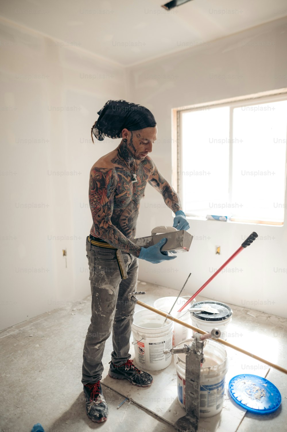 Um homem com tatuagens está pintando uma parede