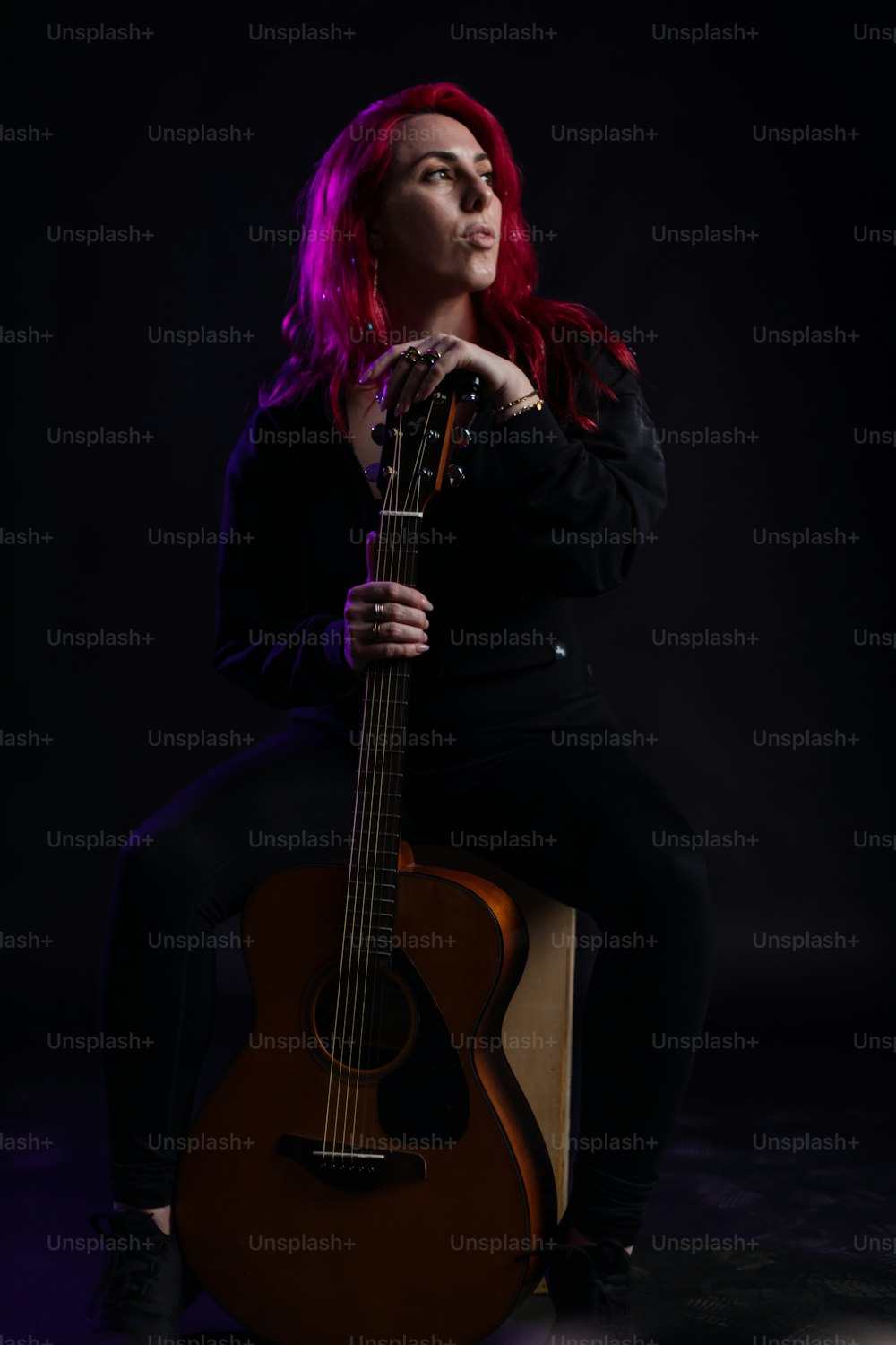 a woman with red hair sitting on a chair holding a guitar