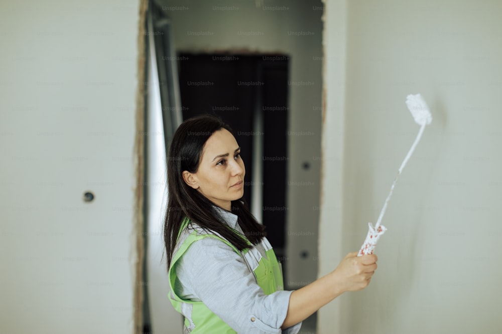 Una mujer pintando una pared con pintura blanca