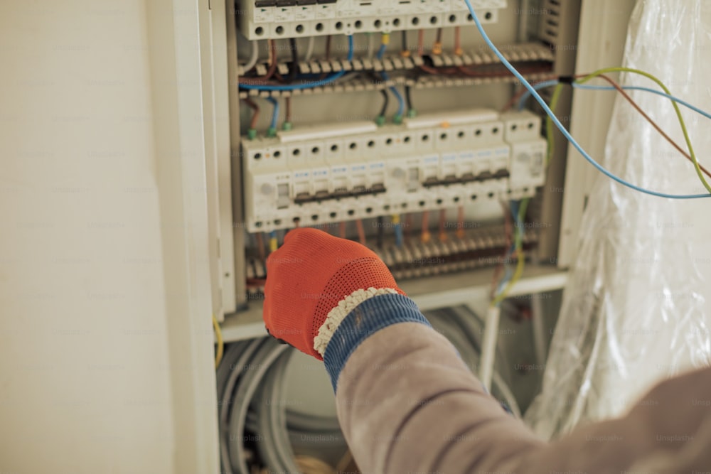 a person with a red glove is in front of an electrical panel