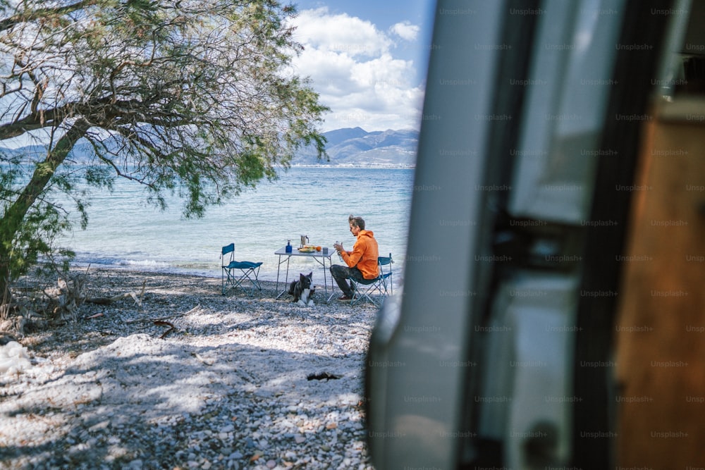 a man sitting at a table next to a lake