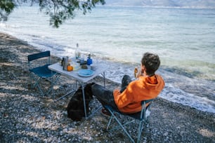 um homem sentado em uma mesa ao lado do oceano