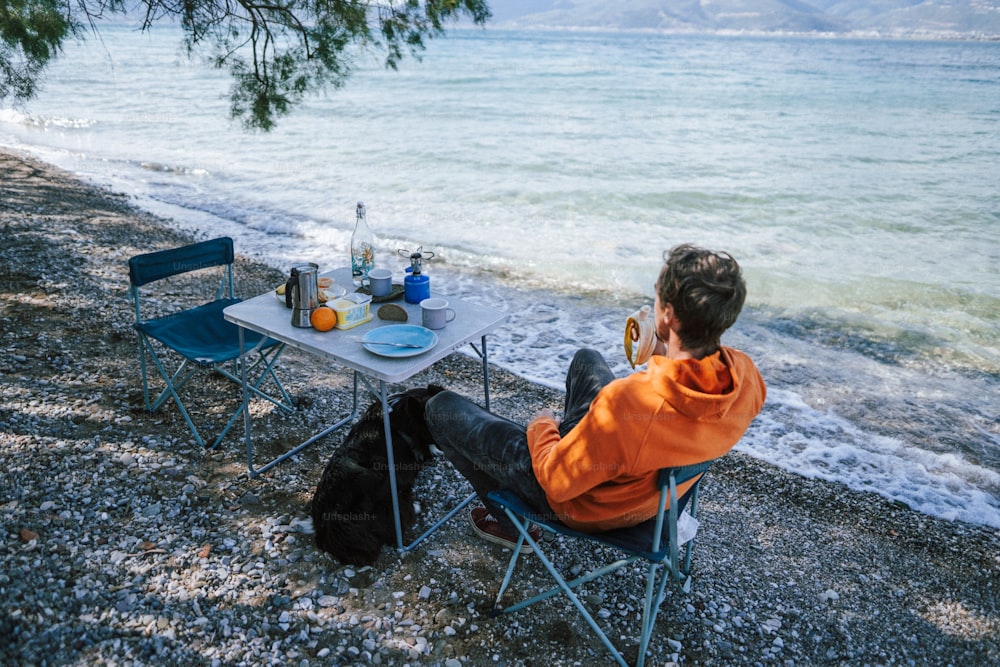 Ein Mann, der an einem Tisch neben dem Meer sitzt