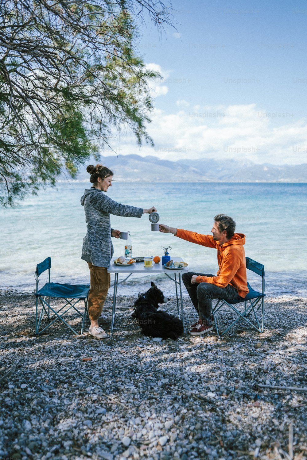 um homem e uma mulher fazendo um piquenique à beira da água
