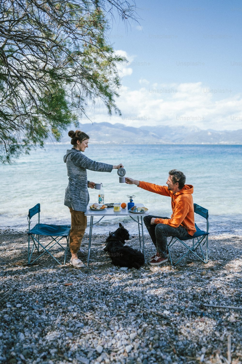 a man and a woman having a picnic by the water