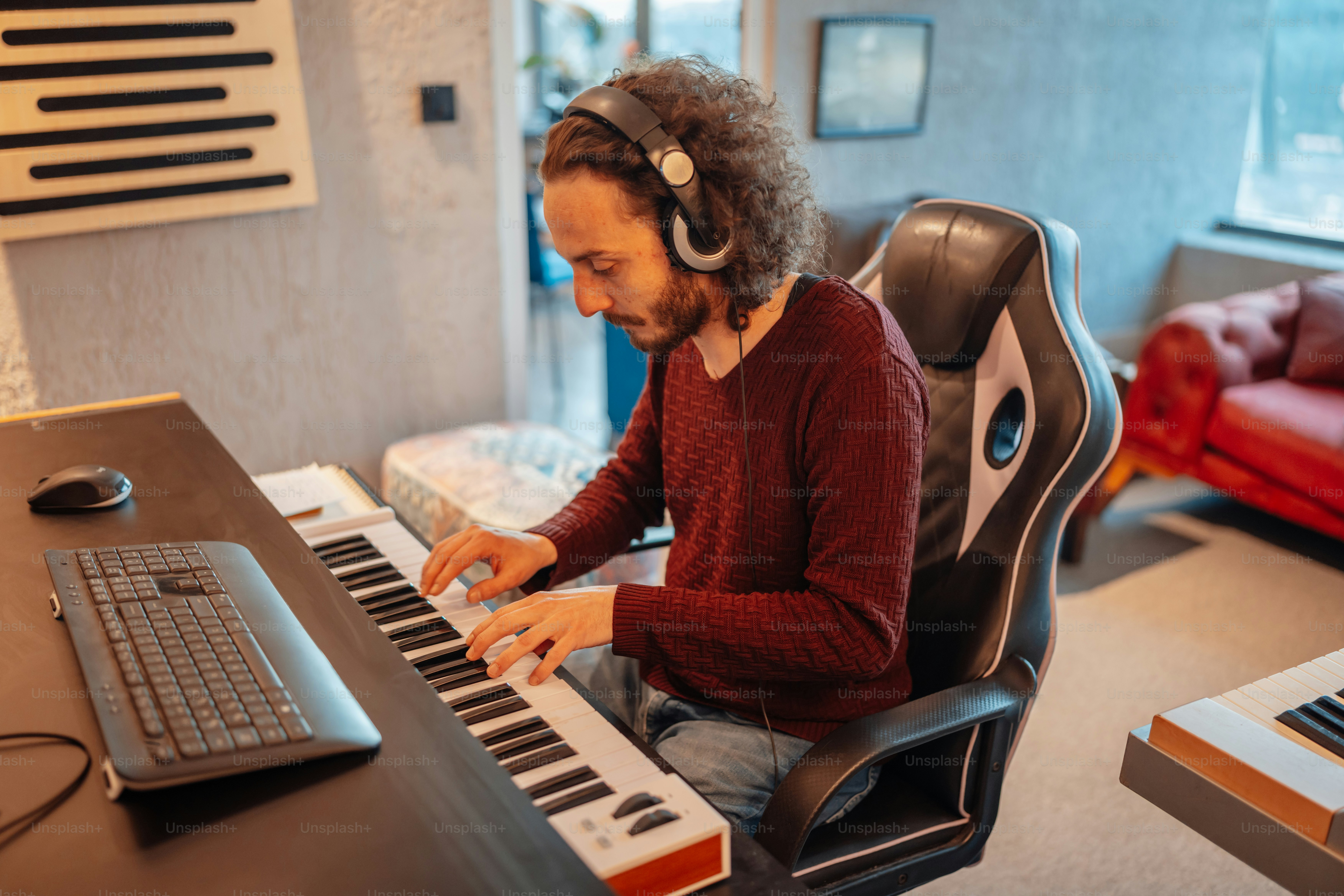 A man sitting at a desk with a keyboard and headphones photo – Music ...