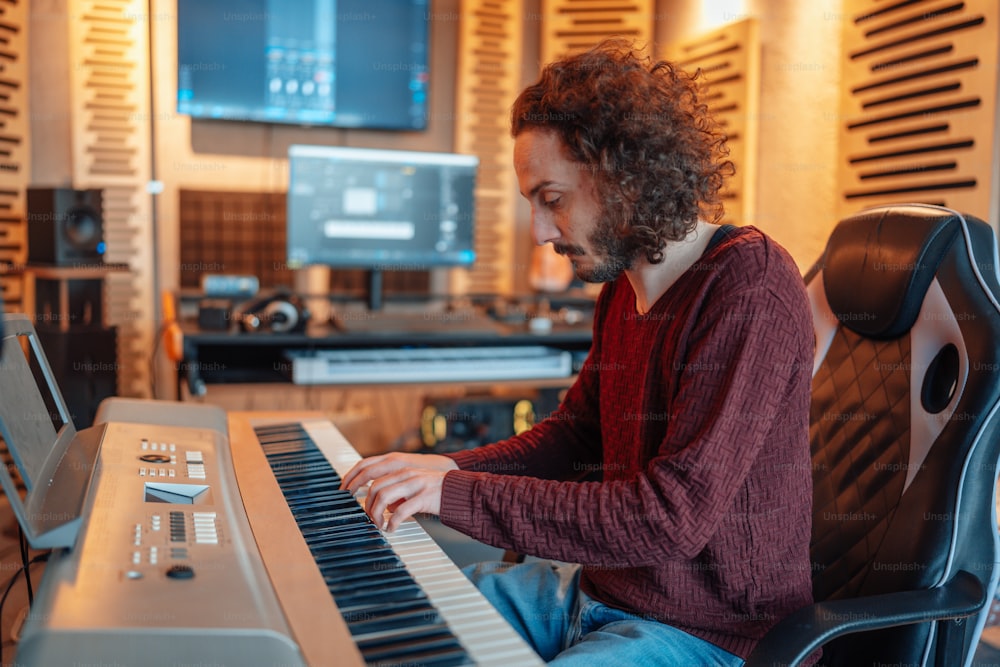 a man sitting at a keyboard in a recording studio
