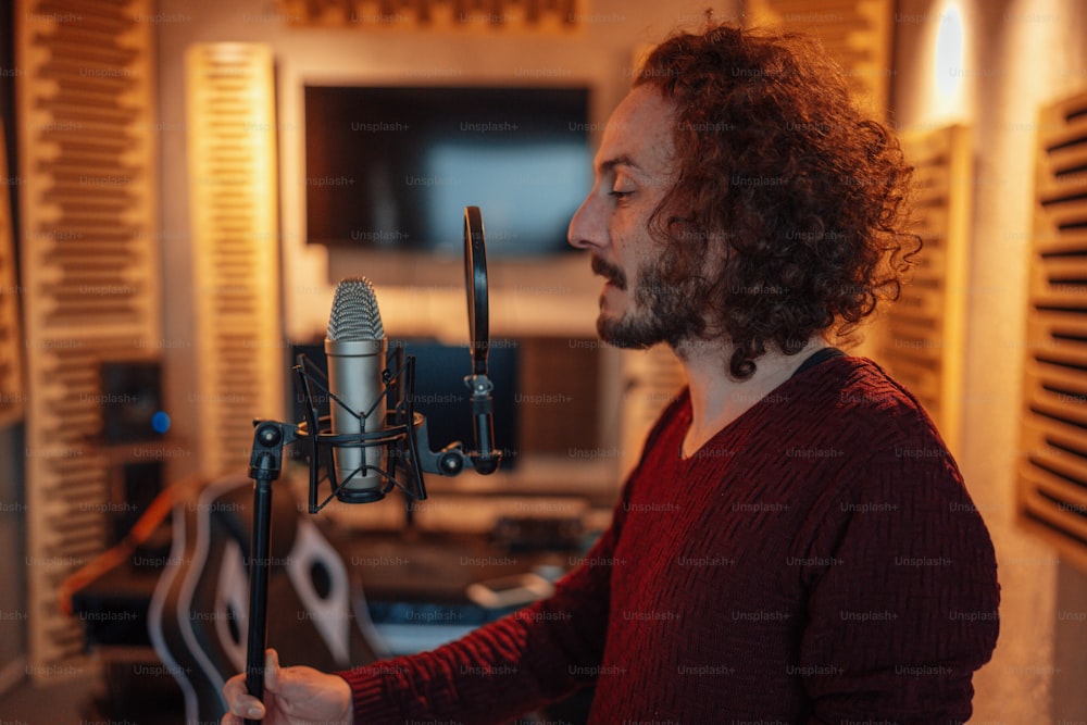 Un uomo con i capelli lunghi sta cantando in un microfono