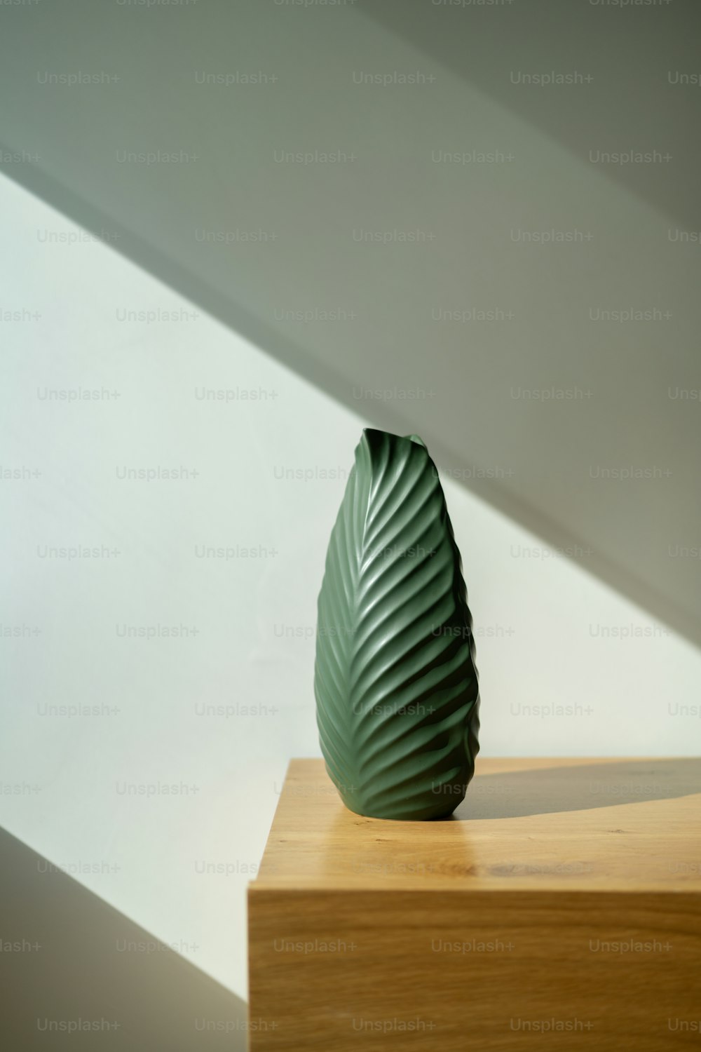 a green vase sitting on top of a wooden table