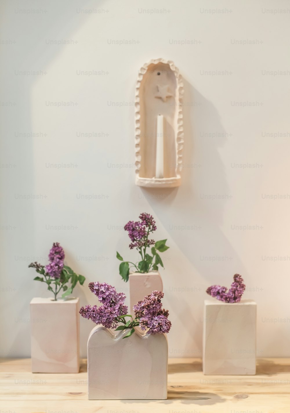 Tres jarrones blancos con flores púrpuras en ellos