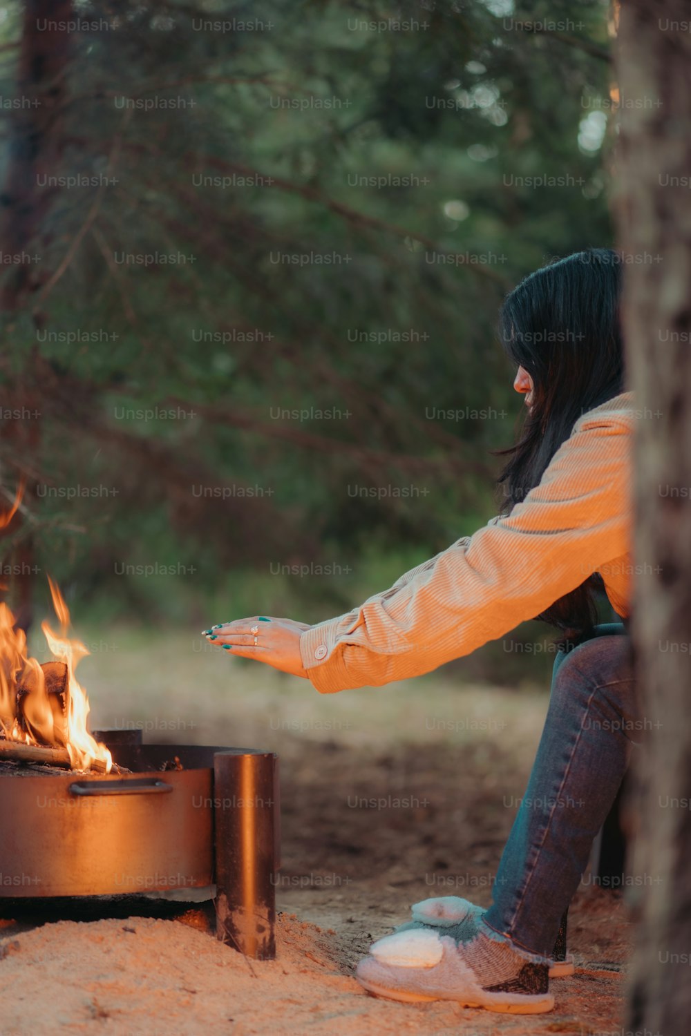 a woman sitting in front of a fire pit