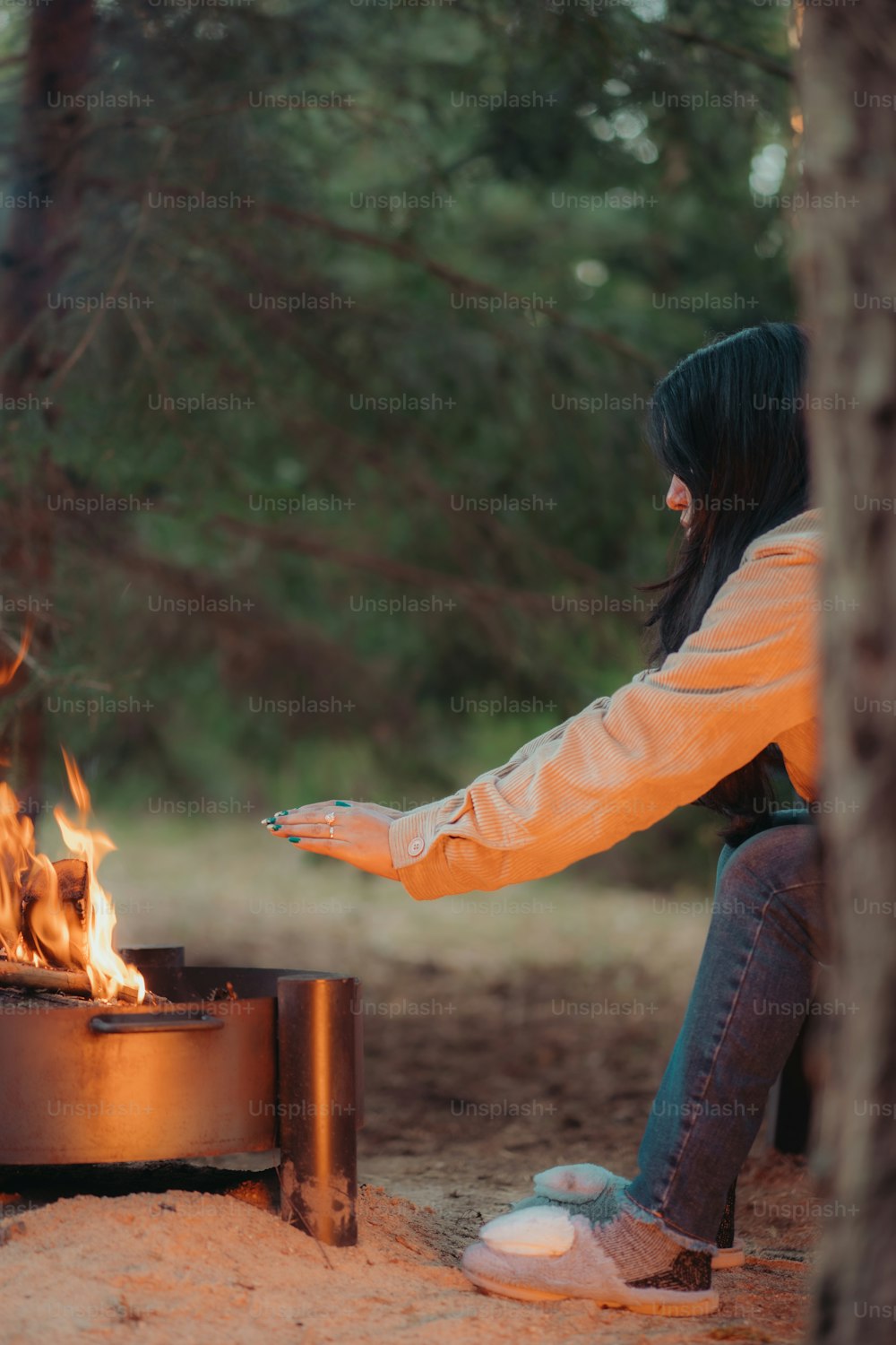a woman sitting in front of a fire pit