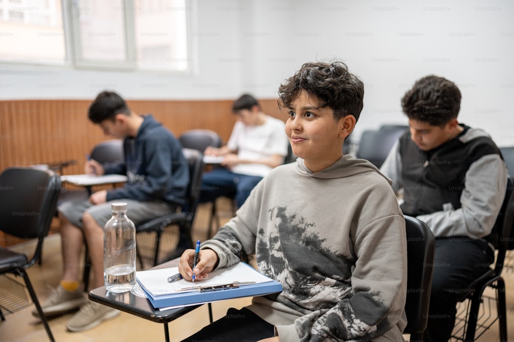 a boy sitting at a table with a book and a notebook in front of him