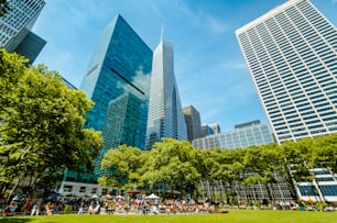 a group of people sitting on a lush green park next to tall buildings