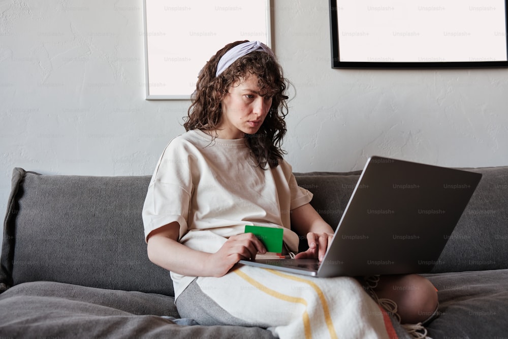 uma jovem sentada em um sofá usando um laptop