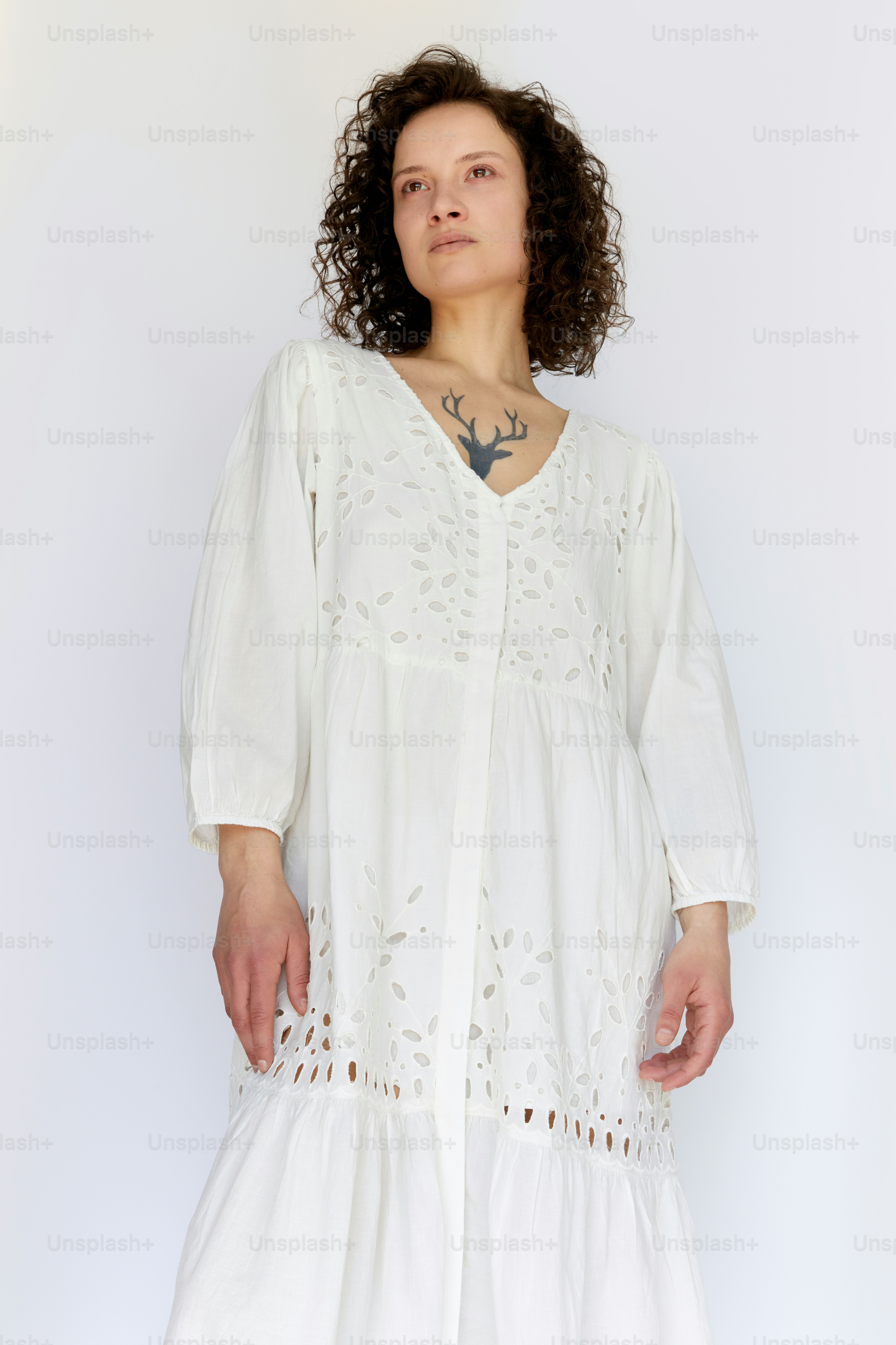 Una donna in un vestito bianco con un tatuaggio sul collo
