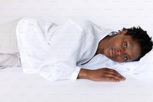 a young boy laying down on a white sheet