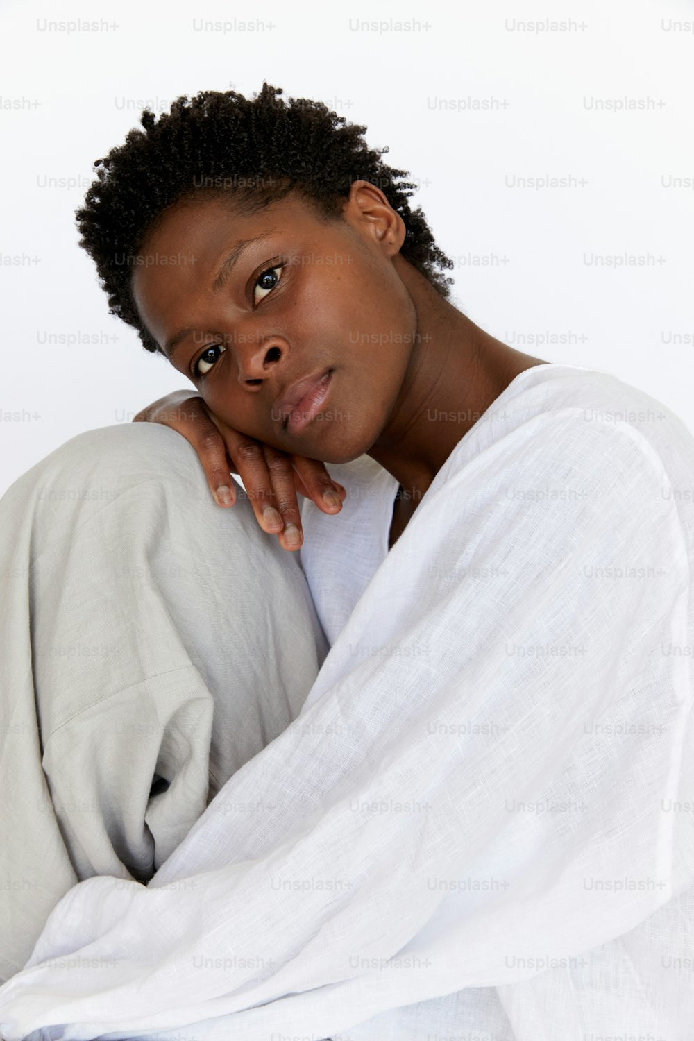 una donna seduta su un letto con una coperta sopra la testa