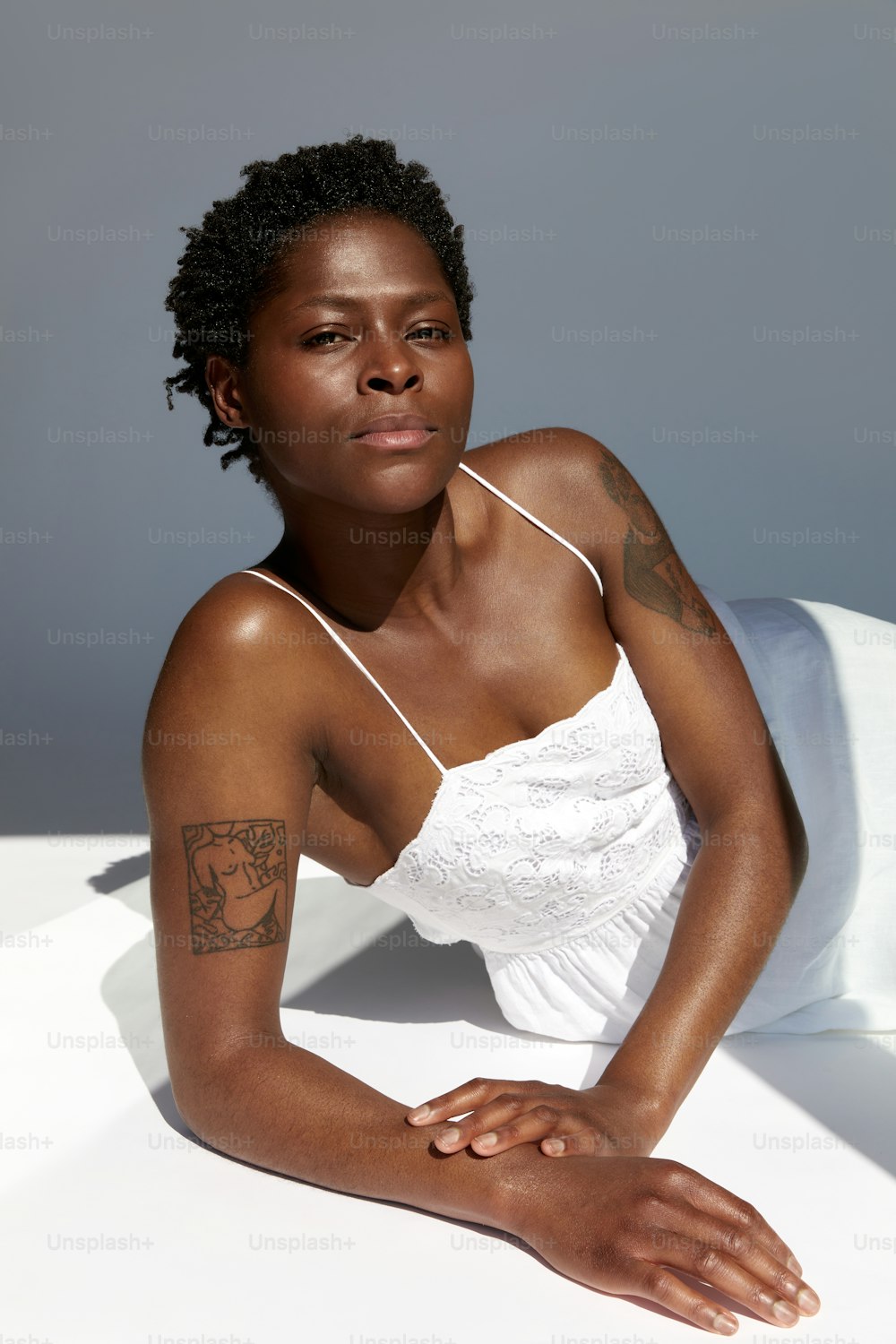 a woman sitting on a bed with a tattoo on her arm