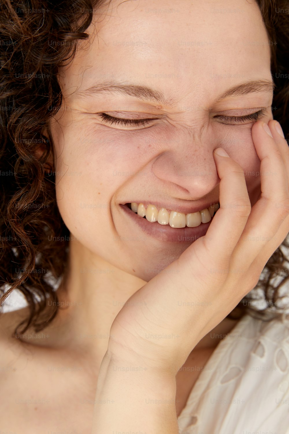 a woman smiling and holding her hand to her face