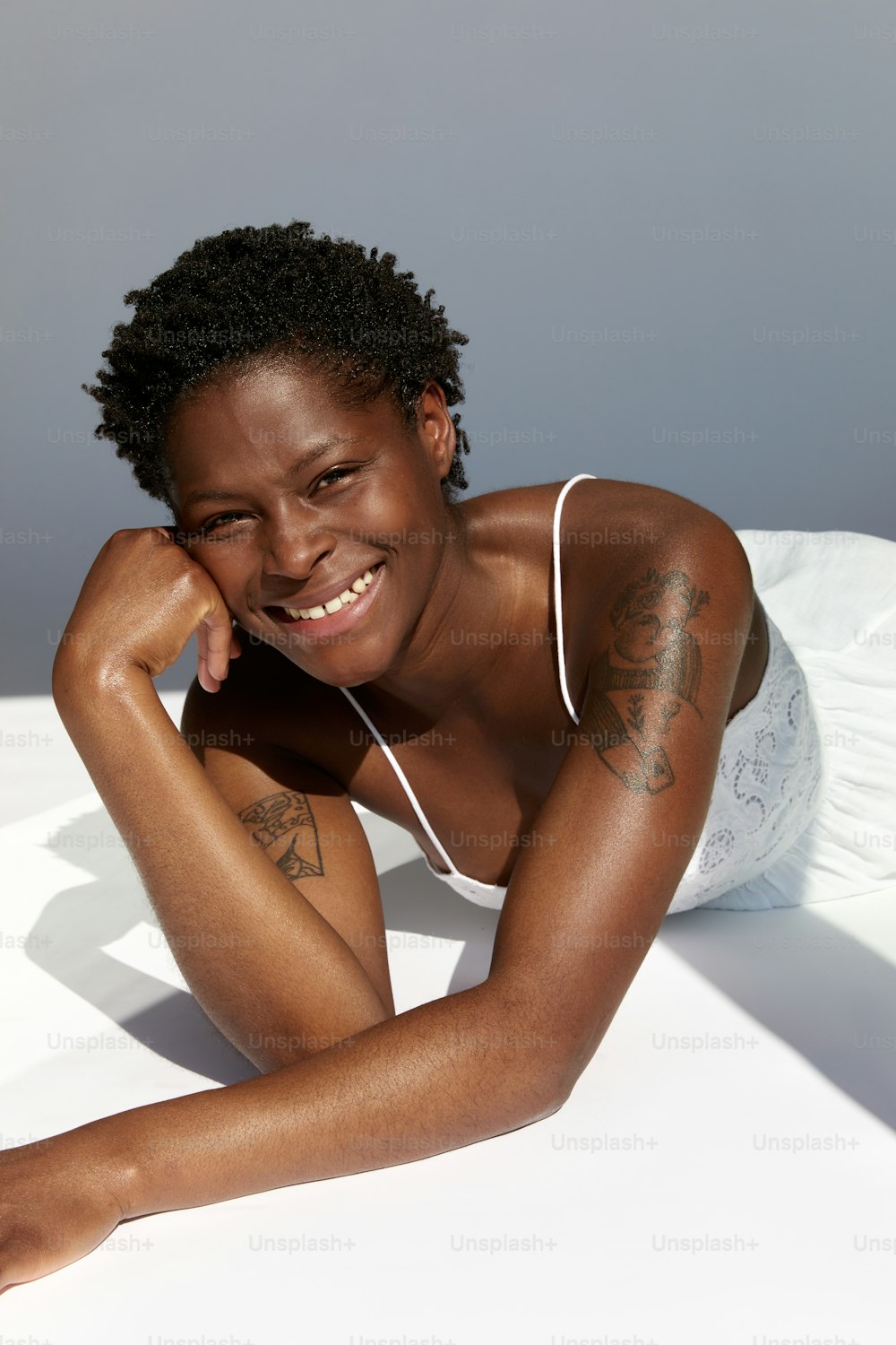Una mujer acostada encima de una cama con una camiseta blanca sin mangas