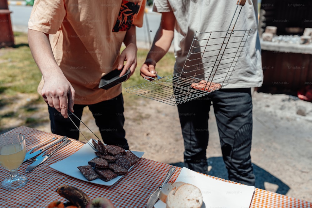 a couple of men standing next to a table with food on it