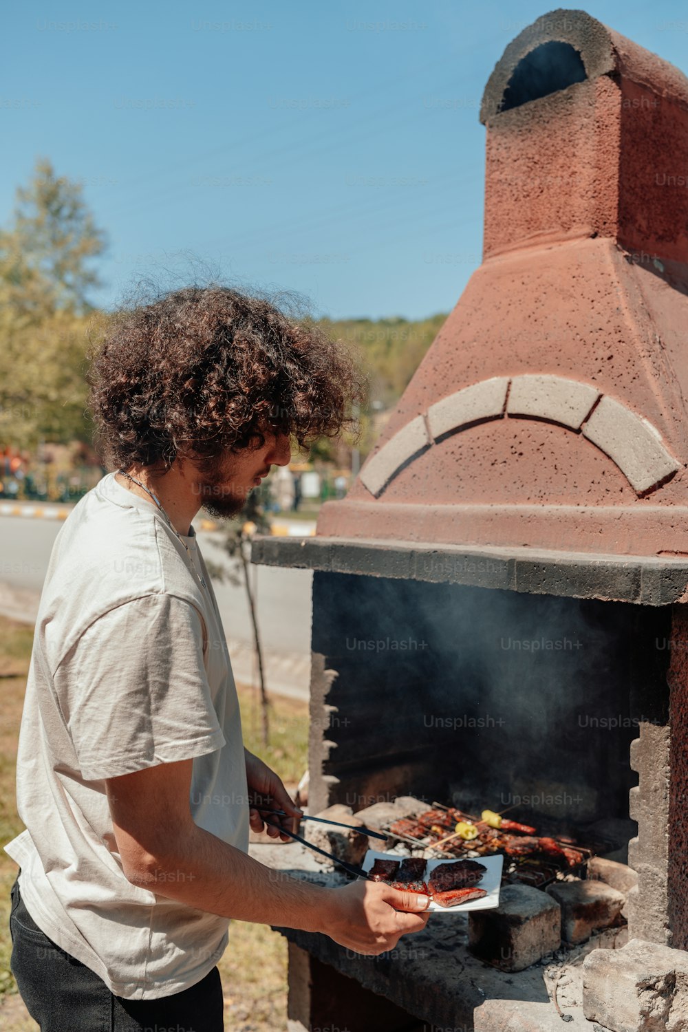 um homem cozinhando comida em uma churrasqueira do lado de fora