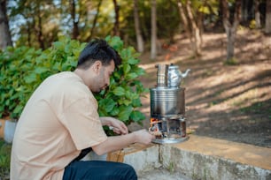 a man sitting on a bench working on a coffee maker