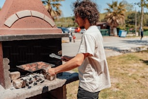 a man cooking food on a grill outside