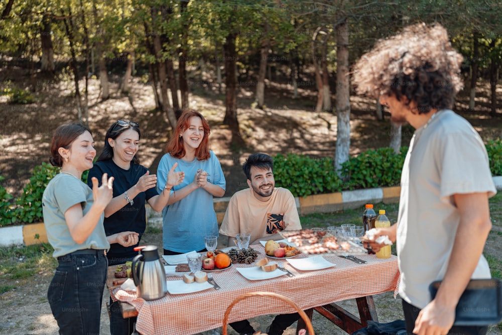 a group of people standing around a table with food on it