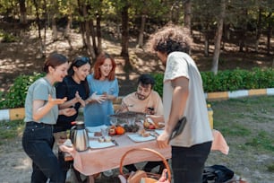 un groupe de personnes debout autour d’une table avec de la nourriture dessus