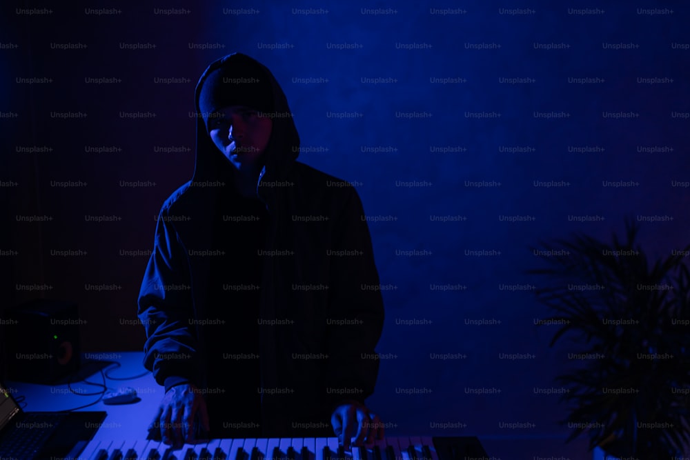 Un hombre parado frente a un teclado en una habitación oscura