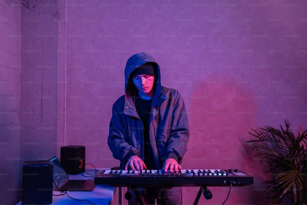 um homem com uma jaqueta com capuz tocando um teclado