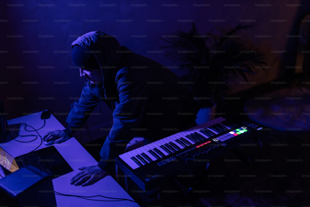 Um homem com um capuz preto está usando um teclado