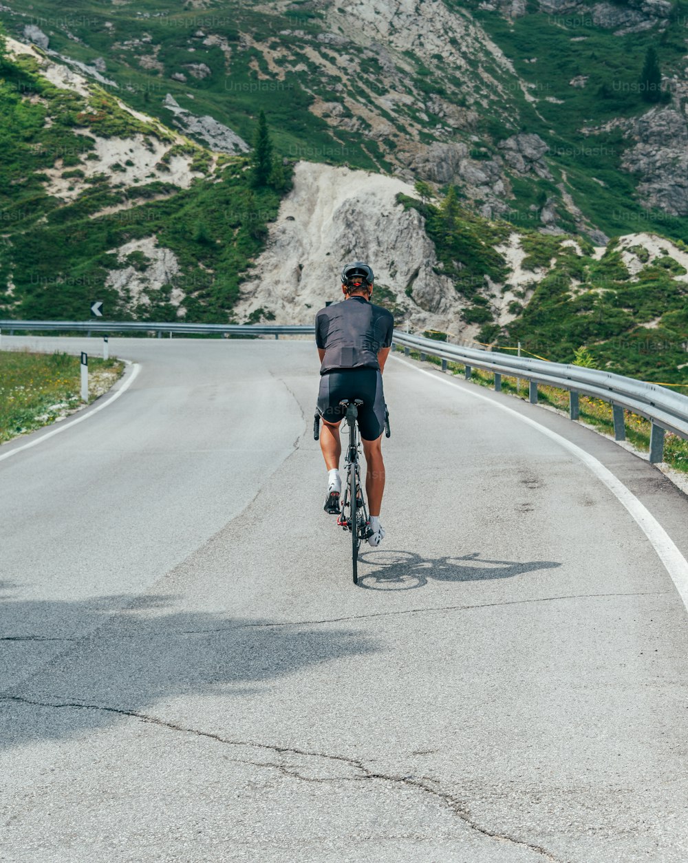 um homem andando de bicicleta por uma estrada sinuosa