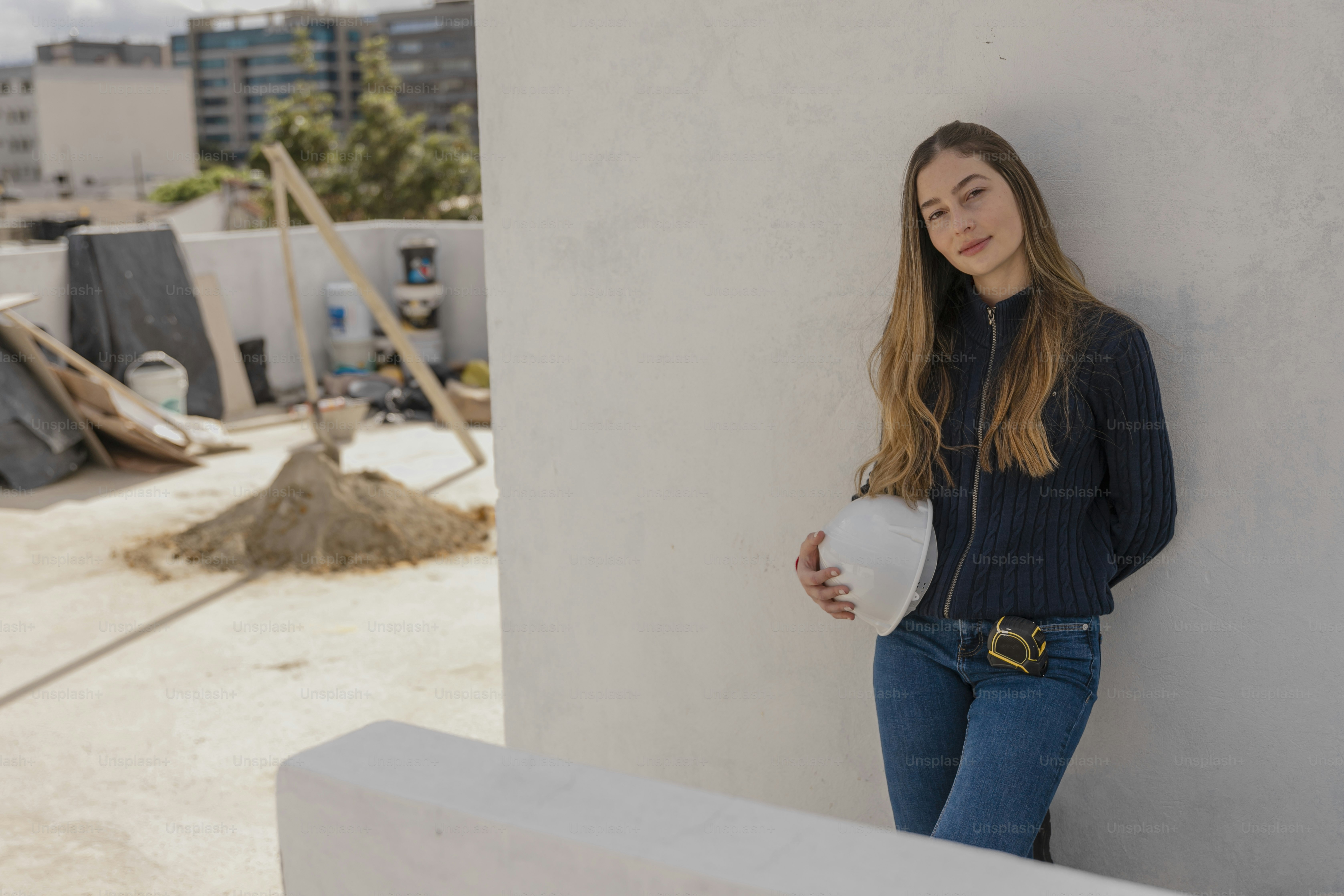 a woman leaning against a wall with a bucket