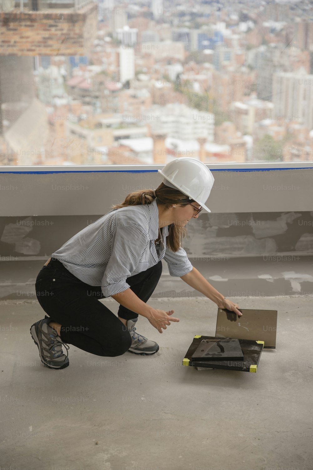 a woman in a hard hat kneeling down next to a box