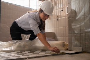 a woman in a hard hat and hardhat working on a tile floor