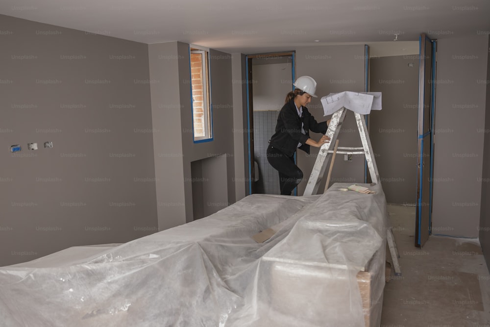 a man standing on a ladder in a room under construction