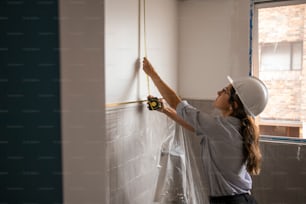 a woman in a hard hat is working on a wall