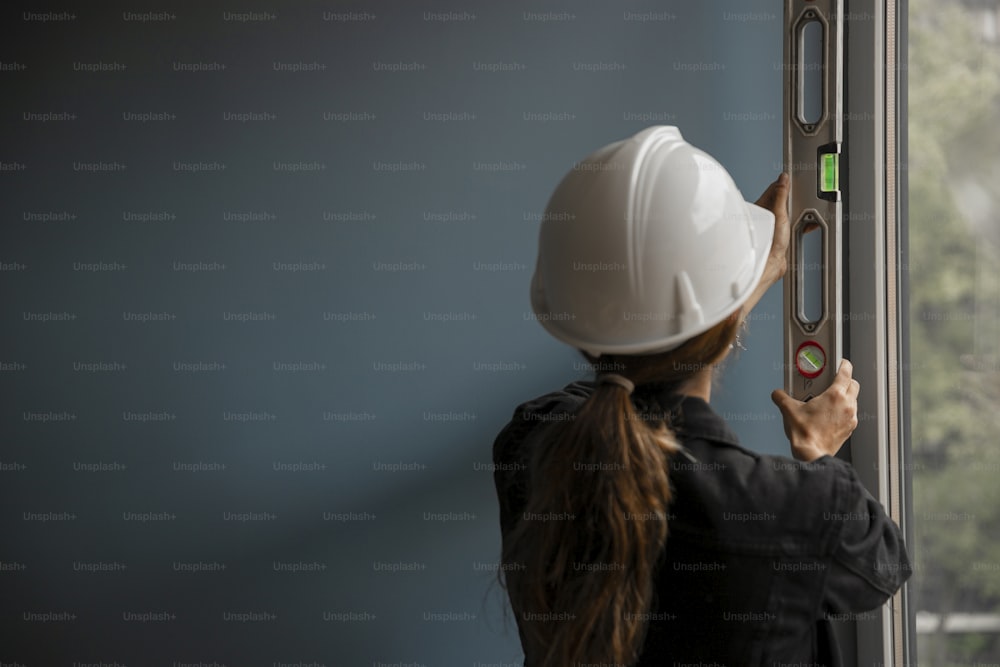 a woman in a hard hat is looking out a window