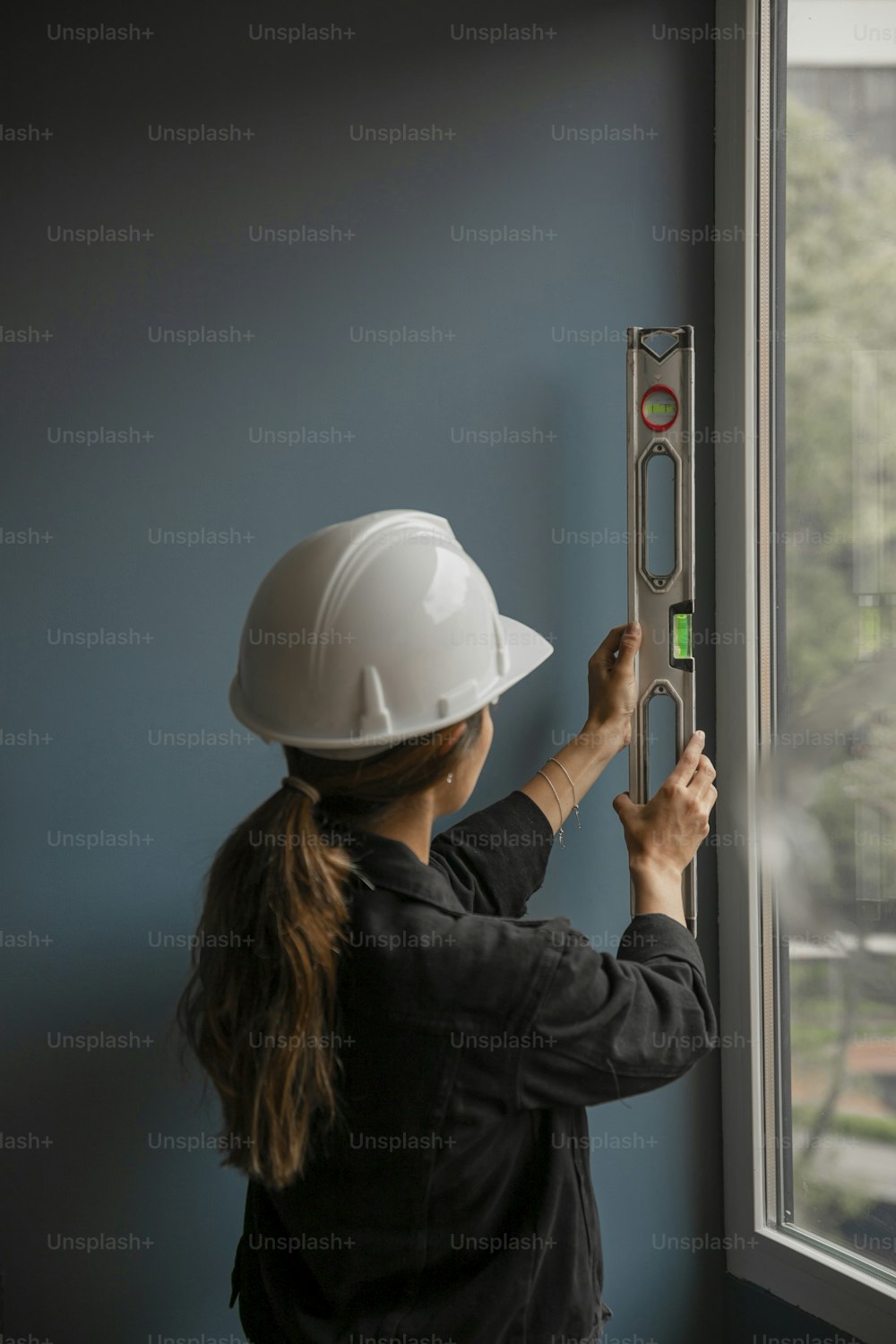 a woman in a hard hat is working on a window