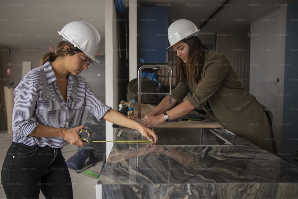 Zwei Frauen mit Schutzhelmen arbeiten an einer Theke