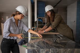 two women in hard hats working on a counter