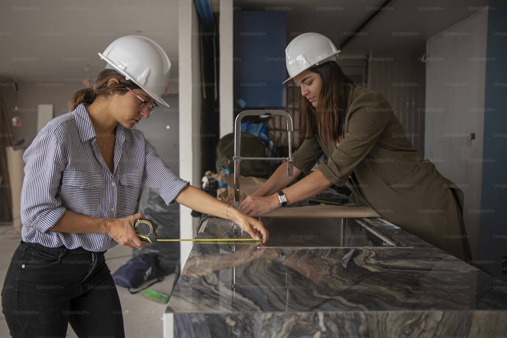 two women in hard hats working on a counter