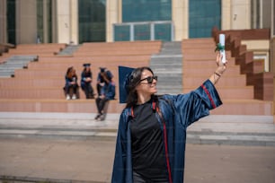Una mujer con un vestido de graduación tomando una foto con su teléfono celular